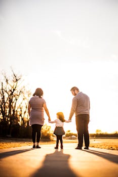 A family of three walks hand in hand at sunset, enjoying togetherness and warmth.